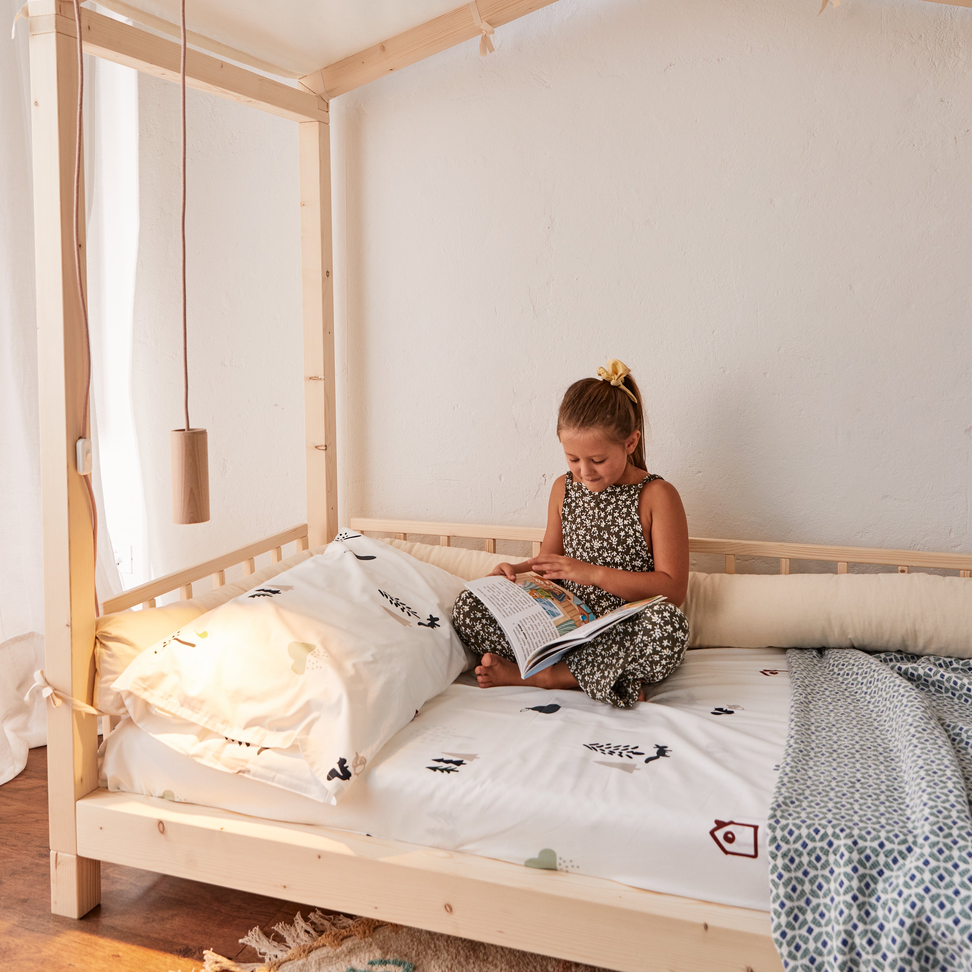 bambina legge un libro seduta su letto montessoriano nabè con sponda e cuscino paracolpi made in Italy