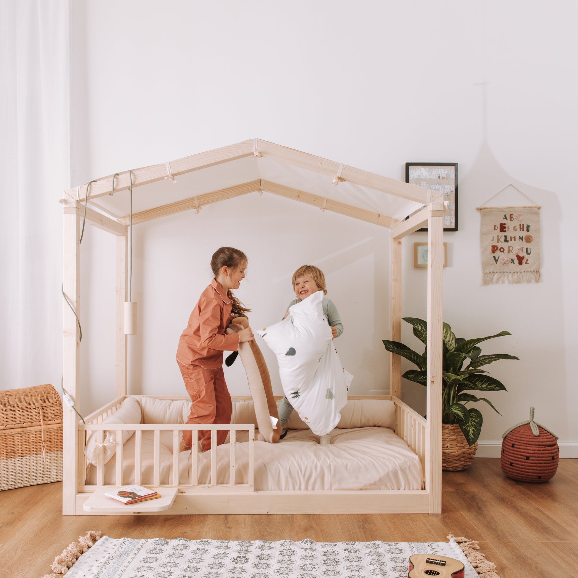 bambini si divertono su letto montessoriano nabè con barriere e baldacchino casetta