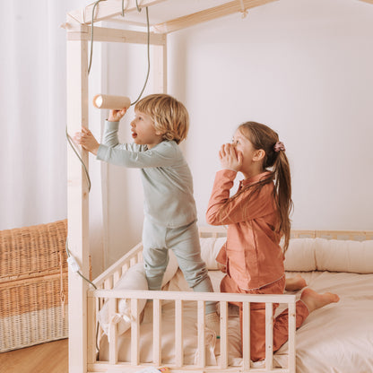 bambini giocano con luce per bambini in legno naturale su letto baldacchino montessori